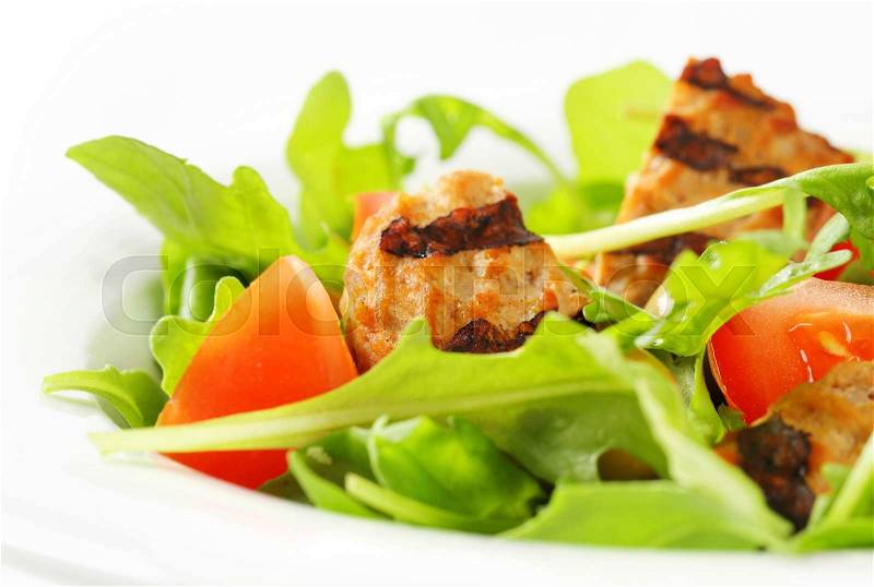Sliced grilled patty on nest of rocket salad with tomato and olives, stock photo