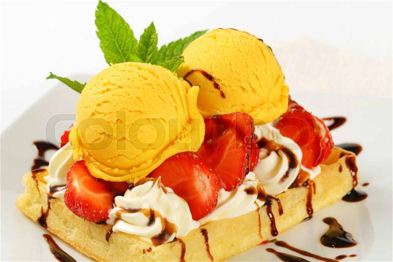 Belgian waffle topped with whipped cream, fresh strawberries and ice-cream, stock photo
