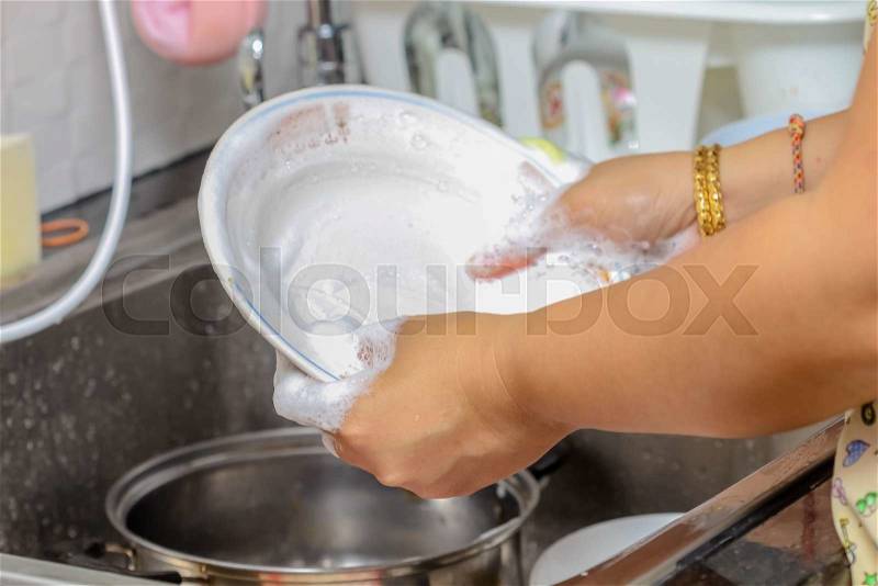 Woman hand wash dish in kitchen sink, stock photo