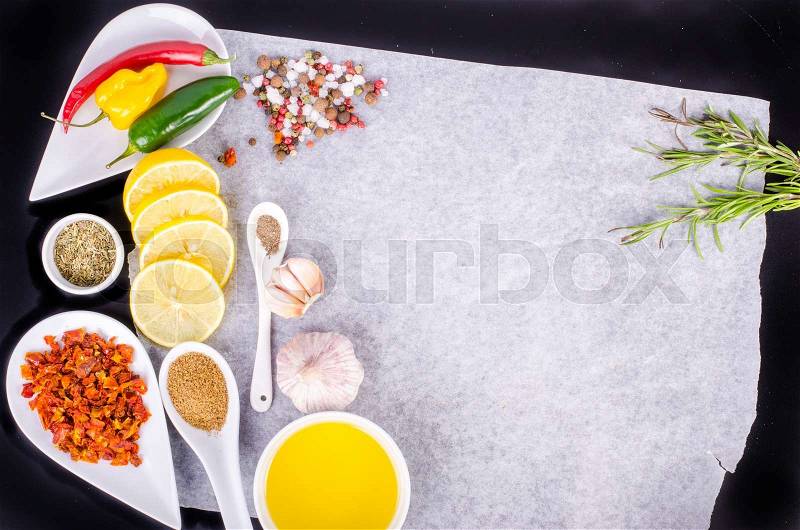Cooking ingredients. Lemon, olive oil, herbs, salt, pepper on paper. Black background. Healthy food concept. Food frame, stock photo