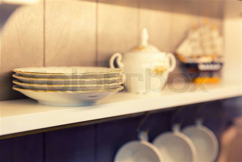 Closeup photo of white plates and kitchen tools in a cupboard, stock photo