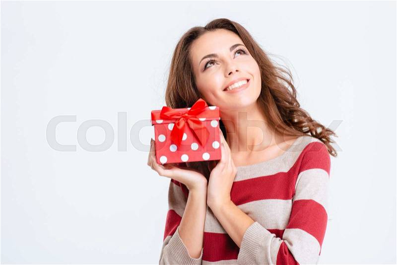Portrait of a happy thoughtful woman holding gift box and looking up isolated on a white background, stock photo