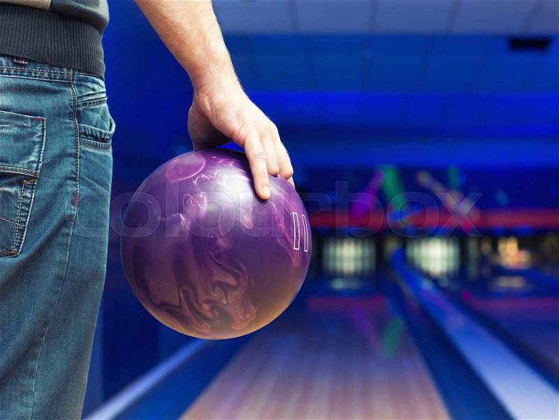 Man holding ball against bowling alley, stock photo