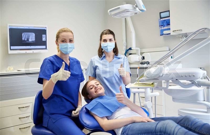 People, medicine, stomatology and health care concept - happy female dentist with assistant and patient girl at dental clinic office, stock photo