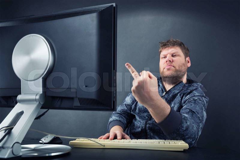Fat angry man sitting at desk looking at monitor screen, stock photo