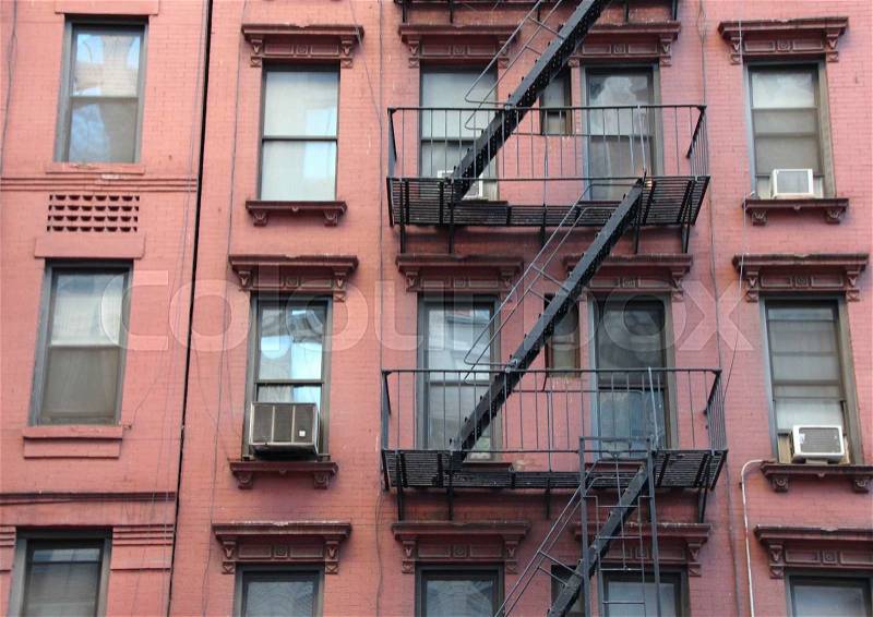Fire Escape Steel Ladder on Urban Red Apartment House Facade in New York, stock photo