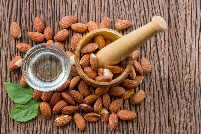Almonds seed and almond oil on wooden background, stock photo