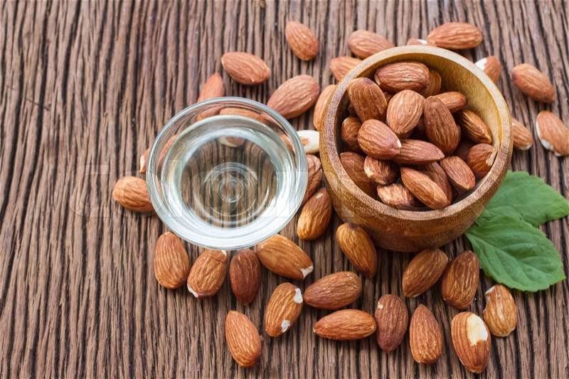 Almonds seed and almond oil on wooden background , stock photo