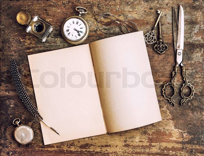 Open diary book and antique writing tools on wooden background. Vintage style toned picture, stock photo