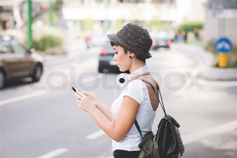 Half length profile of young handsome caucasian brown straight hair woman walking in the city holding a smartphone, looking down the screen - technology, communication, social network concept, stock photo