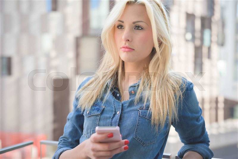Half length of a young beautiful blonde caucasian girl leaning on a windowsill using a smartphone connected online overlooking right - communication, technology, social network concept, stock photo