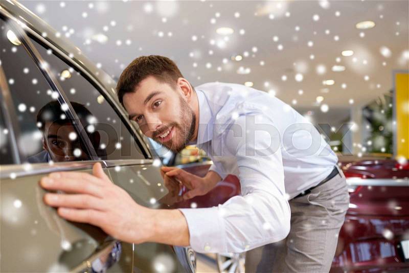 Auto business, car sale, consumerism and people concept - happy man touching car in auto show or salon over snow effect, stock photo