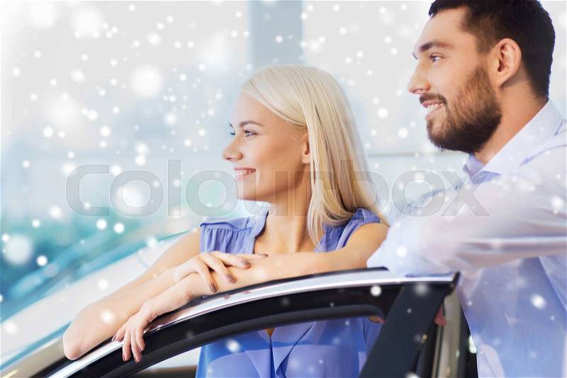 Auto business, car sale, consumerism and people concept - happy couple buying car in auto show or salon over snow effect, stock photo