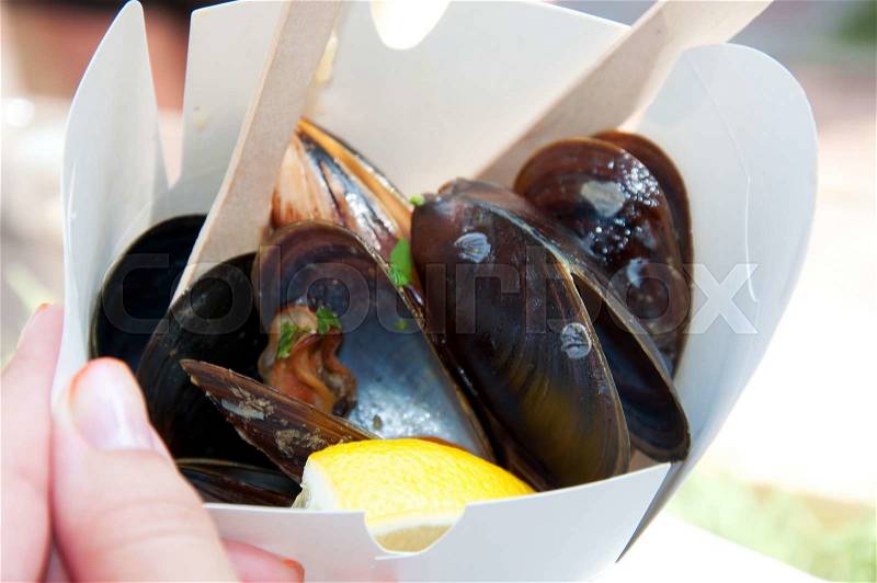 Mussels in a paper take away box with a wooden spoon, stock photo