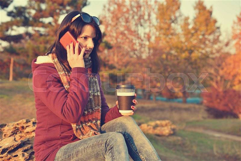 Hipster girl holding cup of coffee and phone. Vintage photo, stock photo