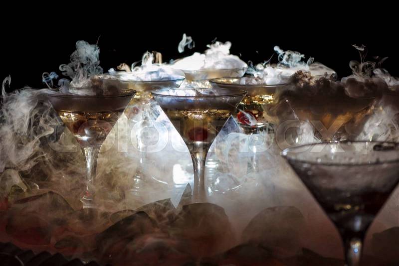 Drink in glasses with the effect of dry ice on black background, stock photo