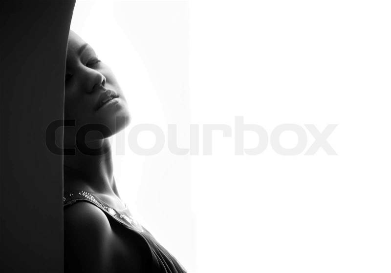 Passionate lady indoors on a white background. Black and white photo with artistic darkness and shadows, stock photo