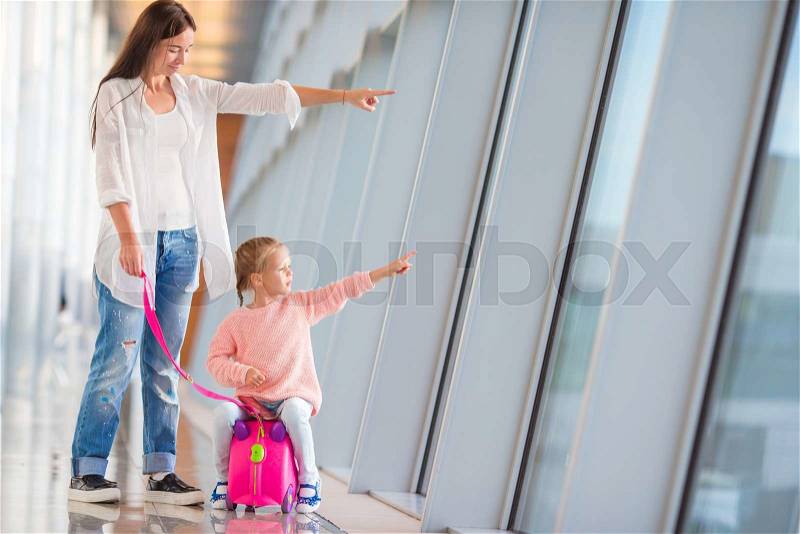 Happy family at airport sitting on suitcase with boarding pass waiting for boarding, stock photo