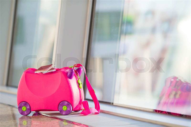 Closeup pink small suitcase with passport and boarding pass in airport near window, stock photo