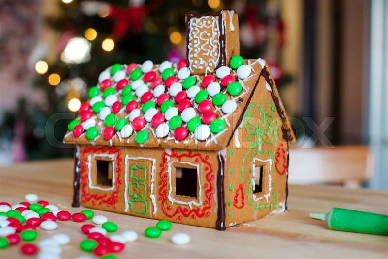 Gingerbread fairy house on a background of bright Christmas tree with light garland, stock photo