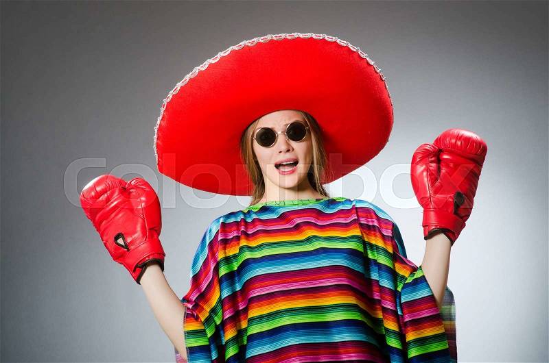 Girl in mexican vivid poncho and box gloves against gray, stock photo