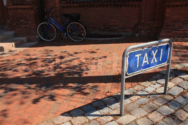 Attention, parking space for taxi and a blue bike in the shadow nearby the train station in the oldest town of Denmark, Ribe, in the beautiful summer, stock photo