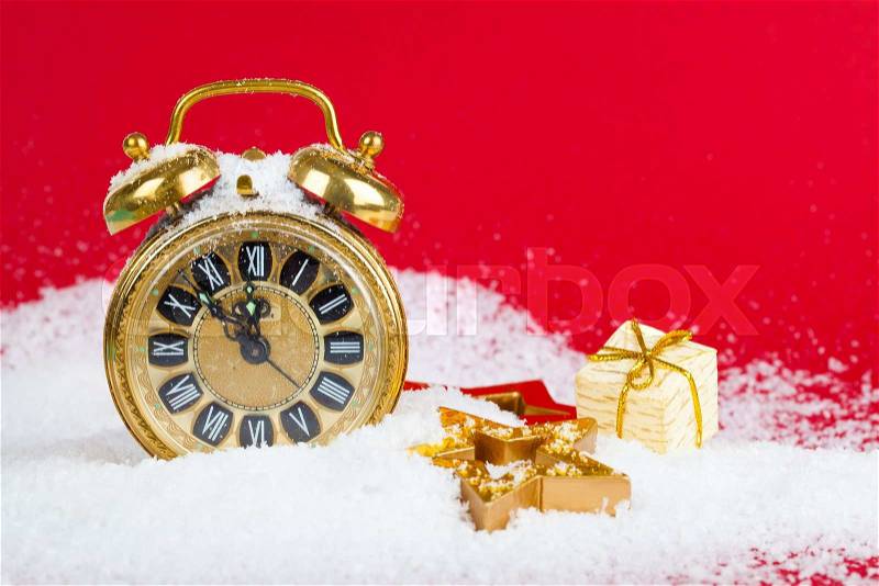 Vintage christmas decoration golden star and antique golden clock in snow on red background, stock photo