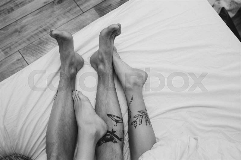 Young adult heterosexual couple lying on bed in bedroom, together with a dog, stock photo