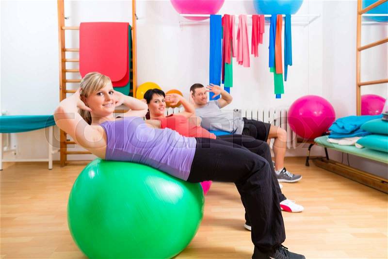 Patients at the physiotherapy doing physical exercises with therapist on training balls, stock photo