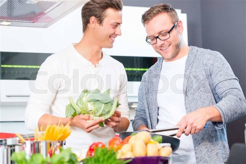 Friends cooking vegetables and meat in domestic kitchen, stock photo