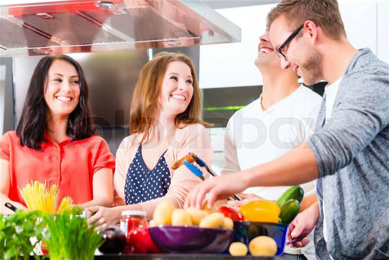 Friends cooking spaghetti and meat in domestic kitchen, stock photo