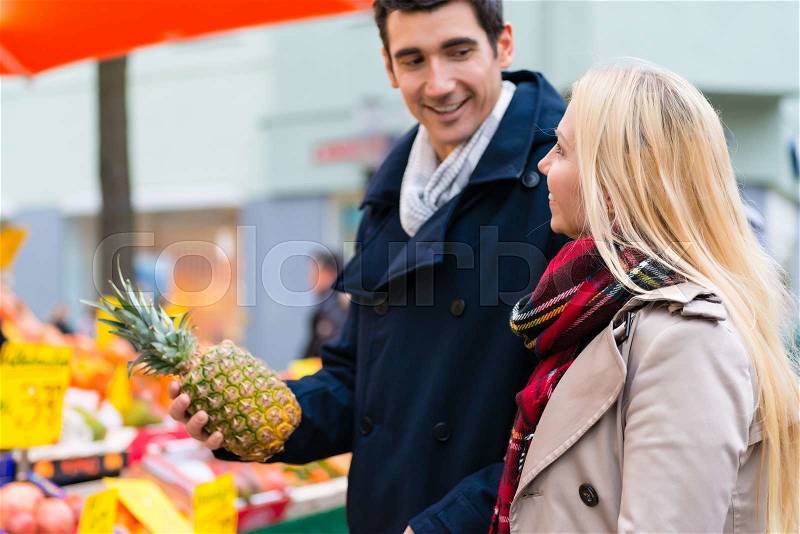 Couple buying groceries on farmers market stand, stock photo