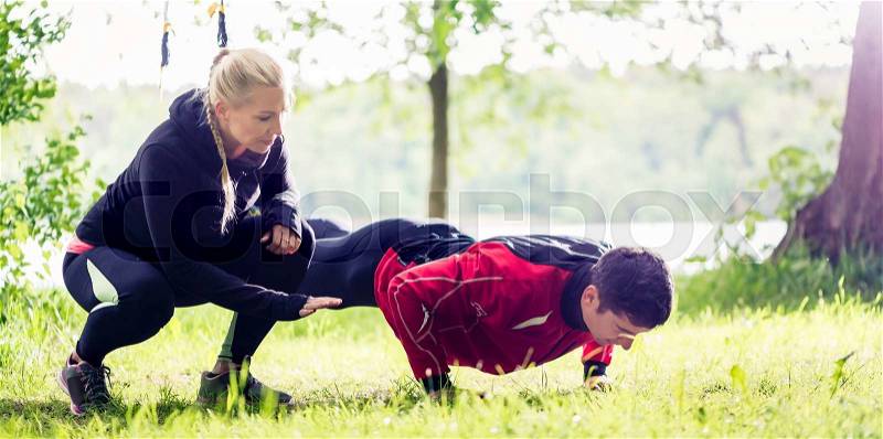 Sport couple outdoors with sling trainer, stock photo
