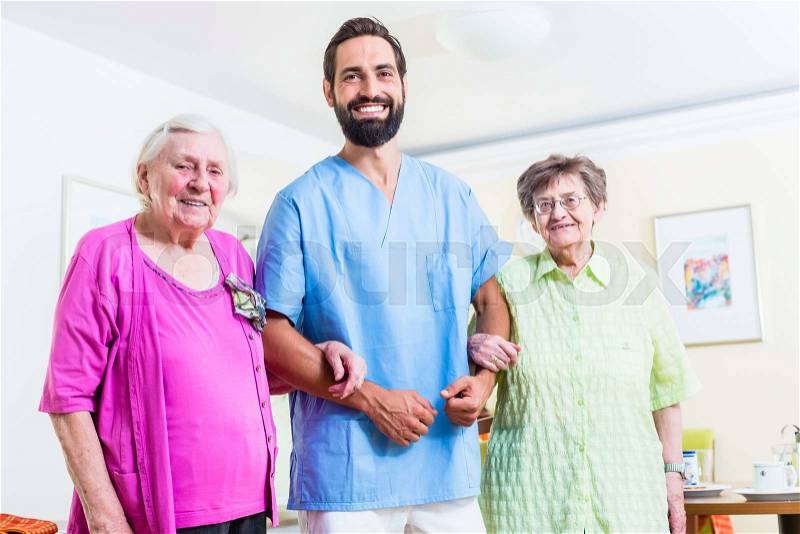 Caregiver with senior women in nursing home, stock photo