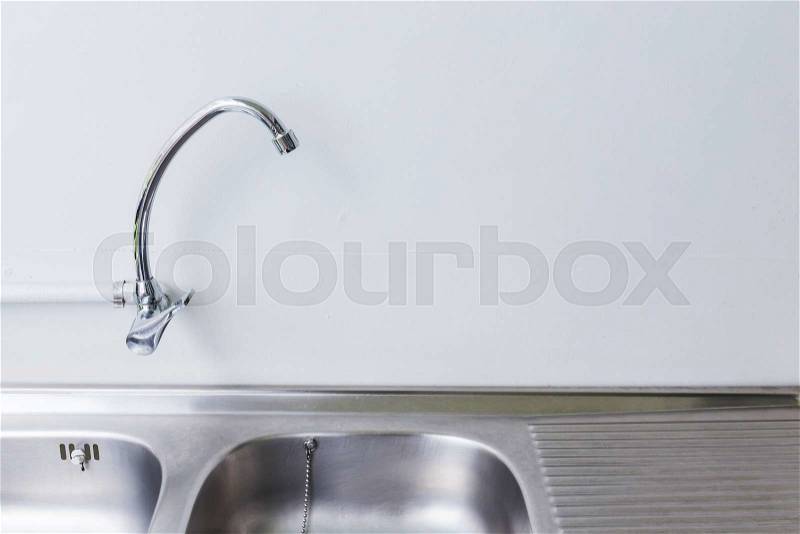 Stainless steel sink and faucet in white kitchen room, stock photo