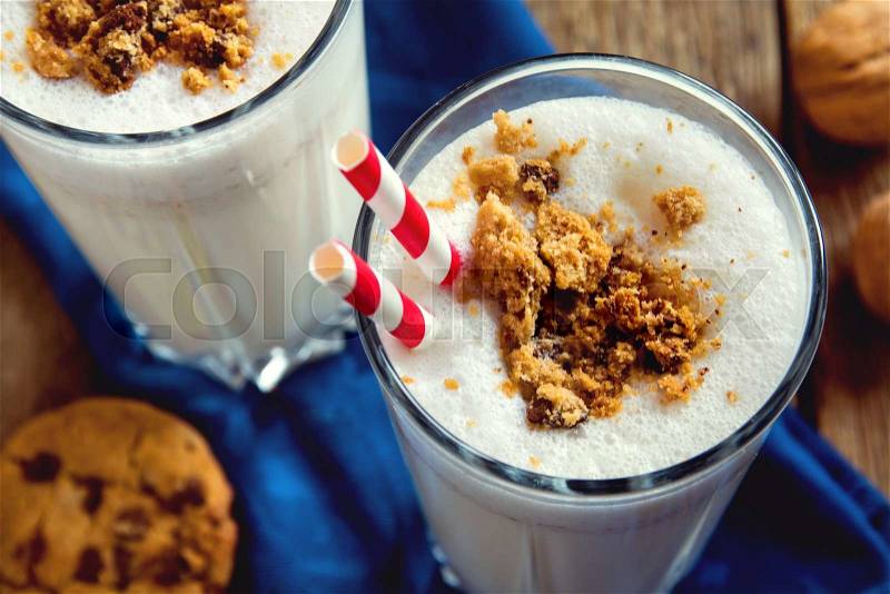 Homemade milkshake with chocolate chips cookies and nuts on rustic wooden table close up, stock photo