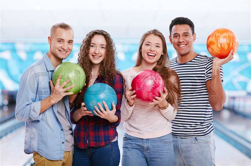 Group of joyful guys and girls with bowling balls, stock photo