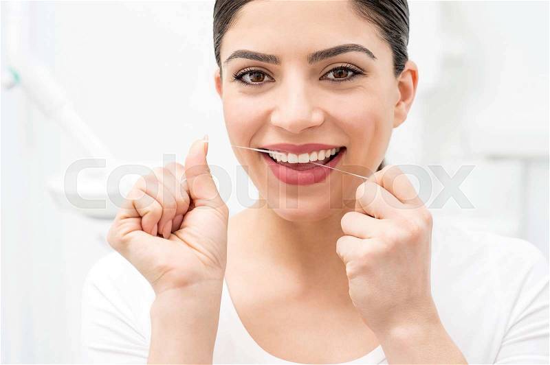 Woman cleaning her teeth by dental floss, stock photo