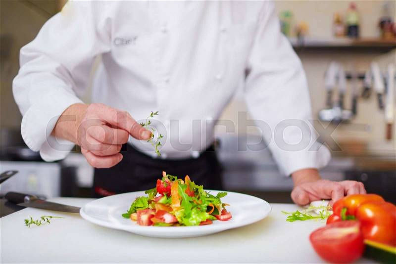 Male chef garnishing dish at the kitchen, stock photo