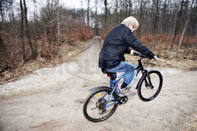 A man riding his push bike in the forest during autumn, stock photo