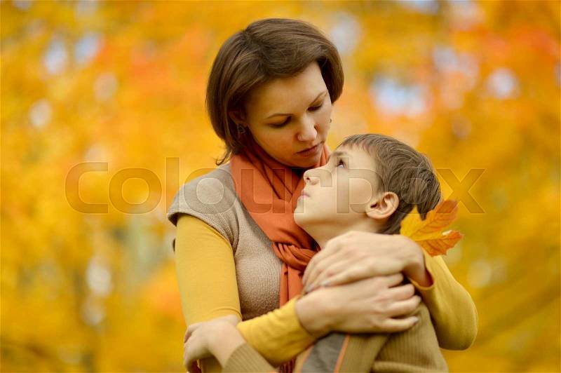 Sad mother with a son on a walk during the fall of the leaves in the park, stock photo