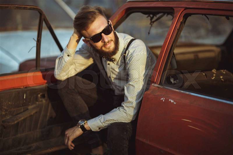 Portrait of a young handsome stylish man, wearing shirt and bow-tie with old cars, stock photo