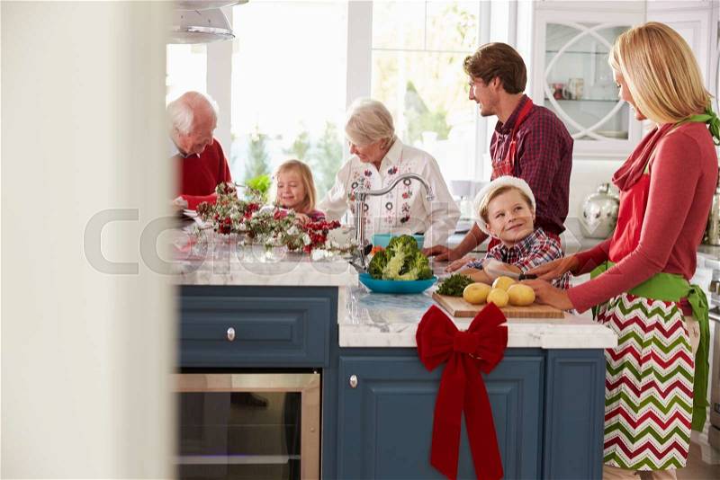 Family With Grandparents Preparing Christmas Meal In Kitchen, stock photo