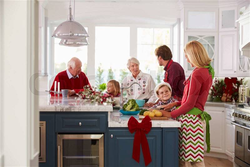 Family With Grandparents Preparing Christmas Meal In Kitchen, stock photo