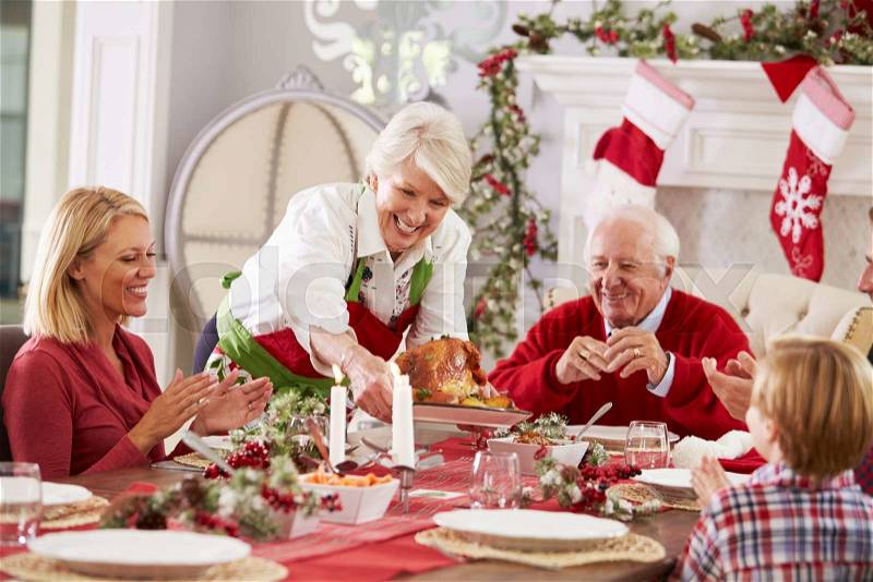 Grandmother Bringing Out Turkey At Family Christmas Meal, stock photo