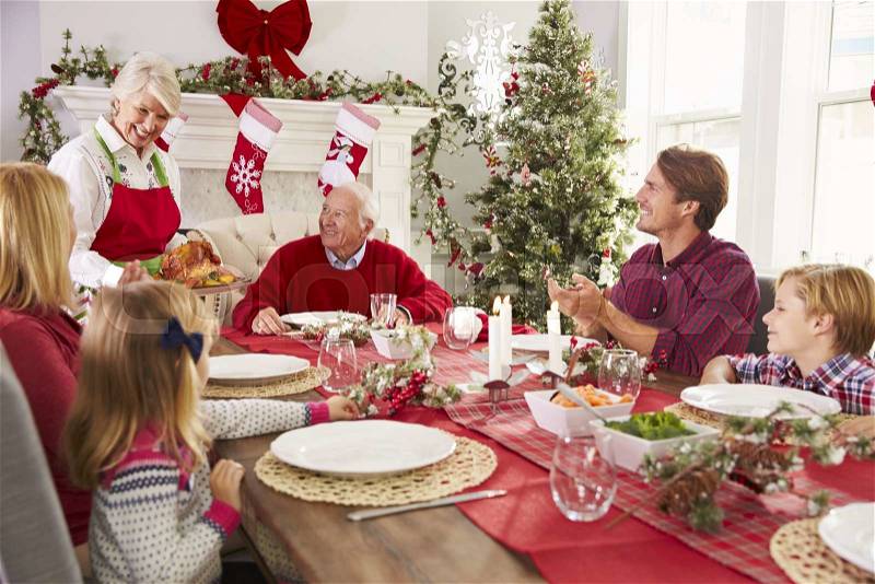 Grandmother Bringing Out Turkey At Family Christmas Meal, stock photo