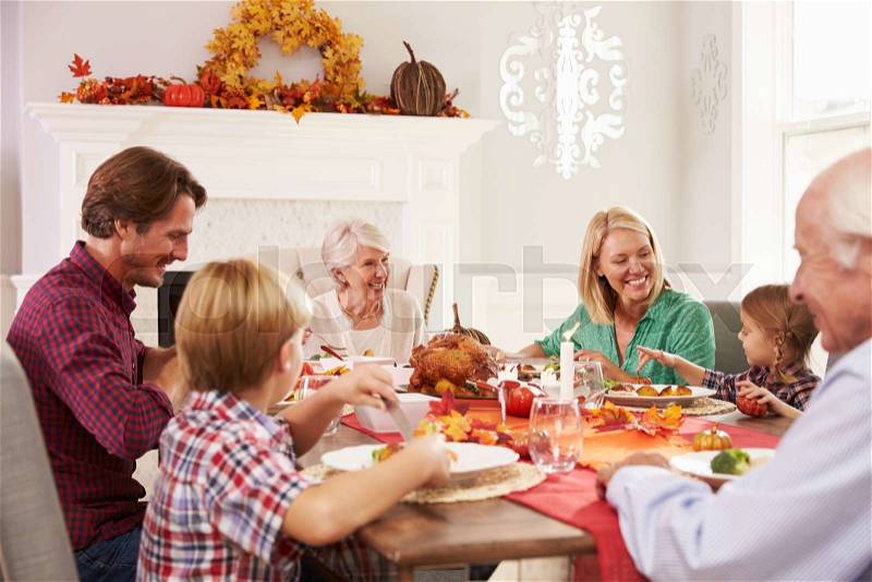 Family With Grandparents Enjoying Thanksgiving Meal At Table, stock photo