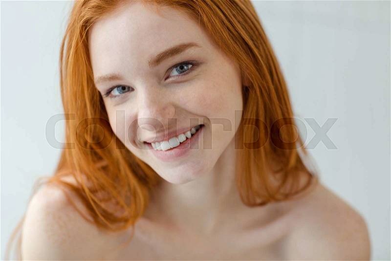 Portrait of a happy redhead woman looking at camera on gray background, stock photo