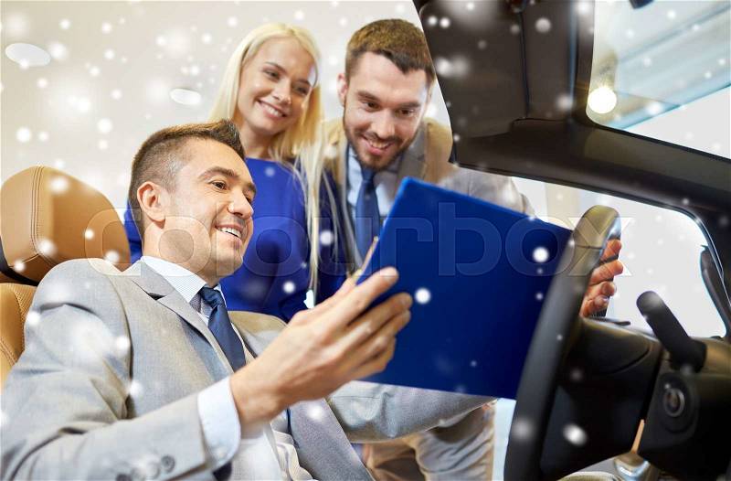 Auto business, car sale, consumerism and people concept - happy couple with car dealer in auto show or salon over snow effect, stock photo