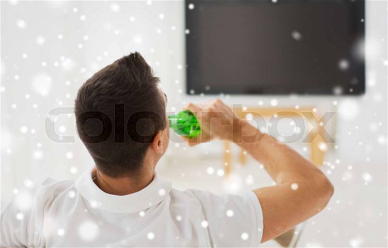 Leisure, technology, mass media and people concept - man watching tv and drinking bottle beer at home from back over snow effect, stock photo